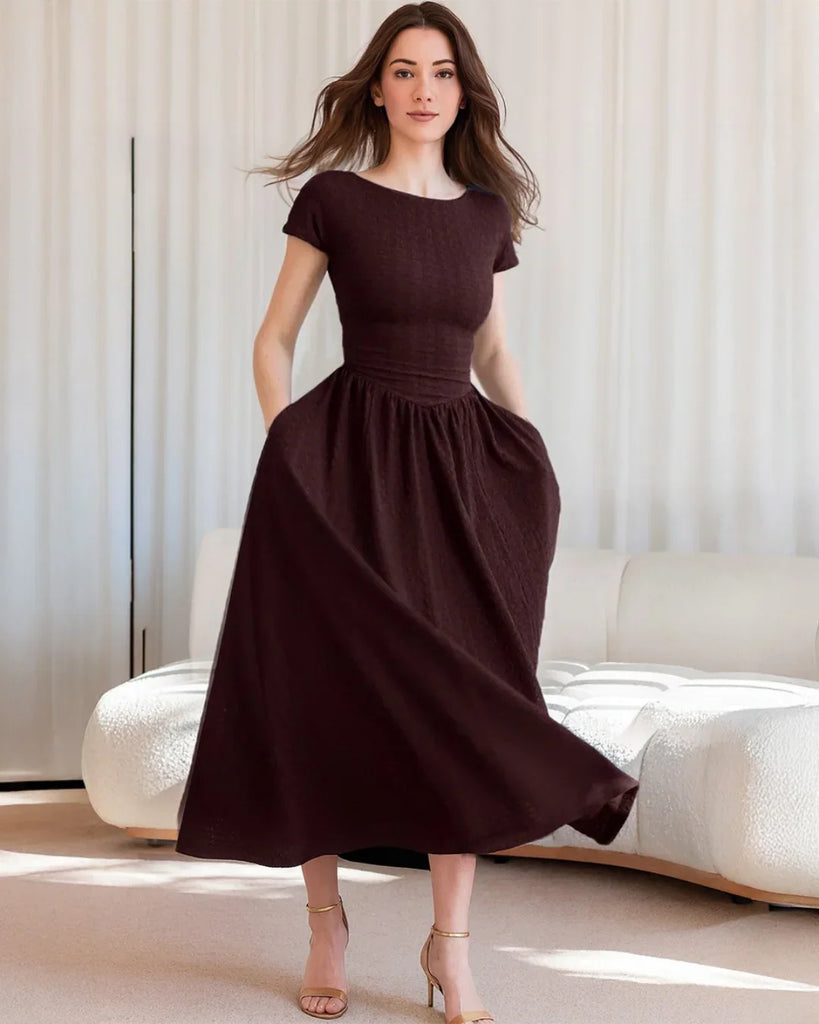 A woman poses in a maroon cap sleeve fit and flare midi dress, showcasing its elegant silhouette against a neutral background.