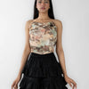 woman wearing a black skirt and a multicolor floral strapless corset top, showcasing a vibrant floral design