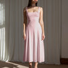 Model showcases a minimal fit and flare dusty pink midi dress, highlighting its elegant silhouette and soft color.

