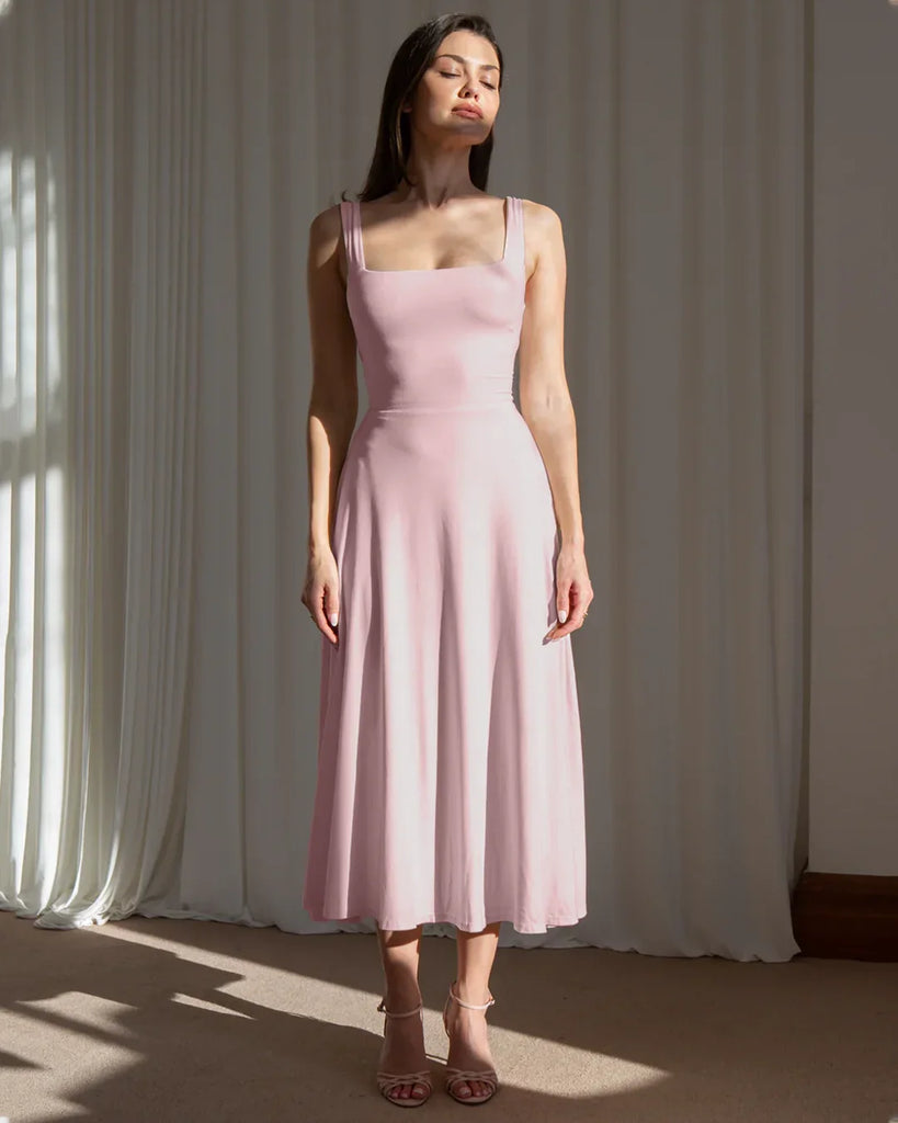 Model showcases a minimal fit and flare dusty pink midi dress, highlighting its elegant silhouette and soft color.
