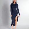 Model in a navy blue ruched dress with long sleeves and a high slit, featuring a ruffle hem.
