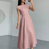 Side view of a woman in a powder pink one-shoulder flared hem midi dress takes a selfie, smiling at the camera.