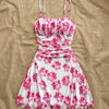 A pink and white mini dress featuring floral patterns and a ruched bust design.