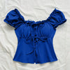 Front view of Royal blue blouse with ruffled puff sleeves and a tie front bow detail.
