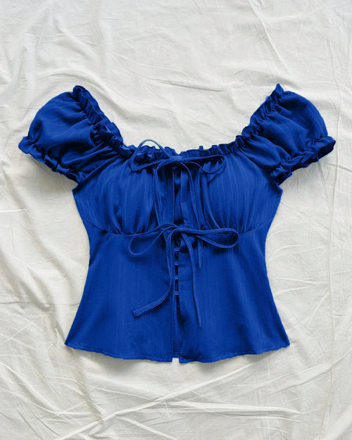 Front view of Royal blue blouse with ruffled puff sleeves and a tie front bow detail.
