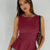 Model in a fitted burgundy peplum top, holding a leopard print bag, showcasing a stylish and trendy outfit.