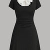 Black mini dress with a round neckline, white collar, and bowknot detail, featuring ruched design.