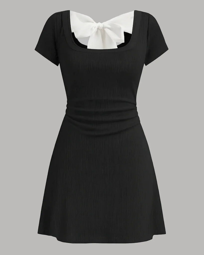 Black mini dress with a round neckline, white collar, and bowknot detail, featuring ruched design.