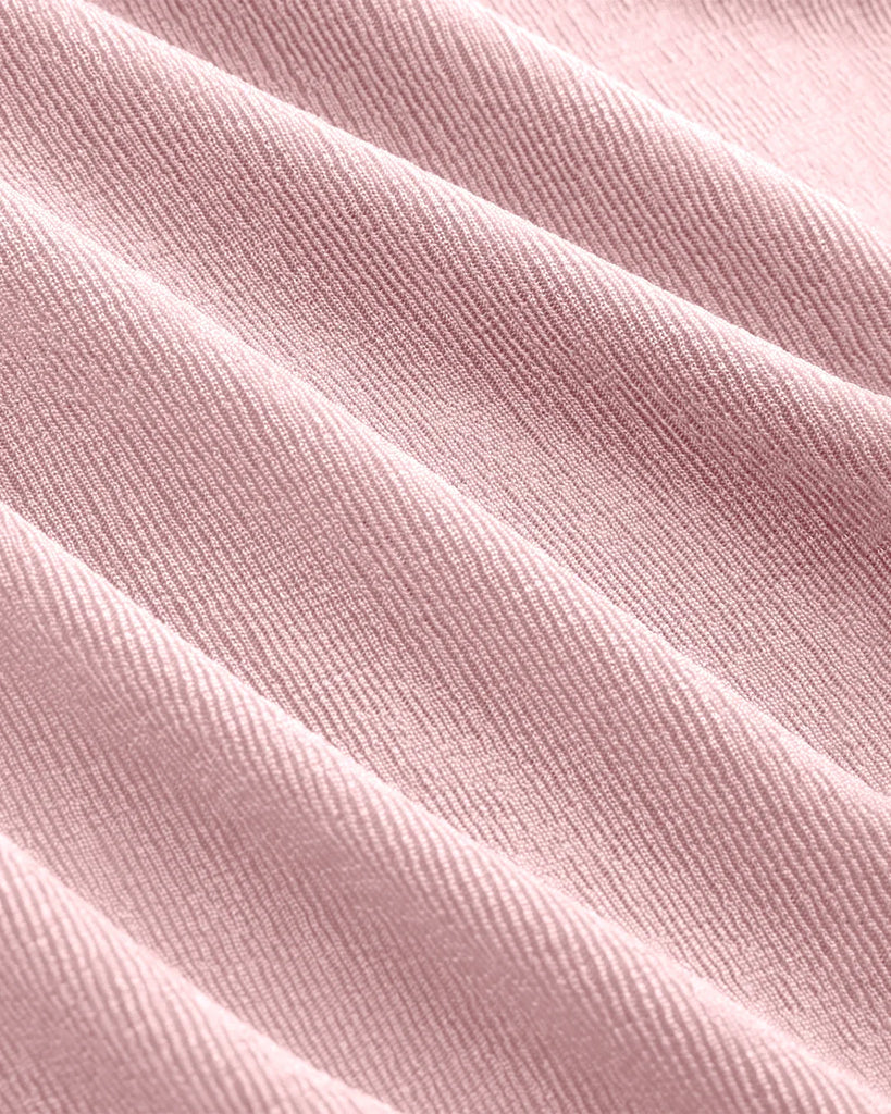 Close up of short sleeve dusty pink top with a ruched front and pointed collar, showcasing a flattering silhouette