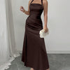 Front view of women wearing a coffee brown ruched halter neck maxi dress with backless tie detail and front slit in a studio setting.
