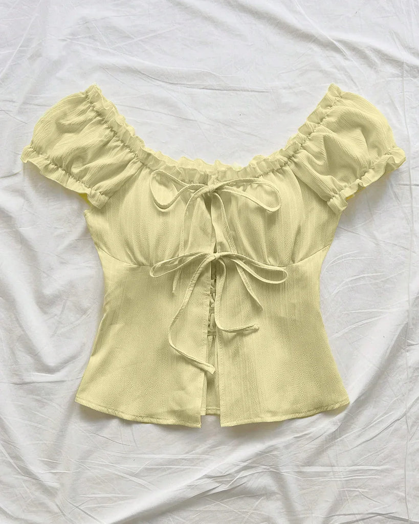 French Vanilla blouse featuring ruffled sleeves and a bow tie front design in a vibrant yellow.