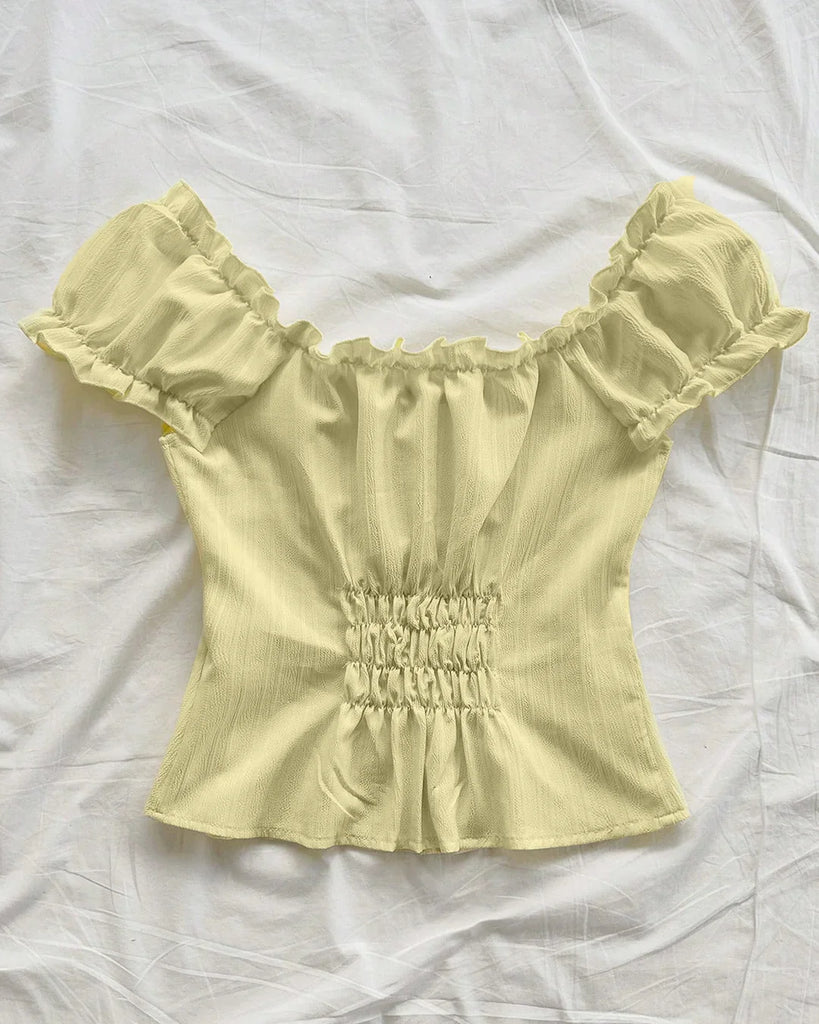 Back view of a French Vanilla blouse featuring ruffled sleeves and a bow tie front design in a vibrant yellow.