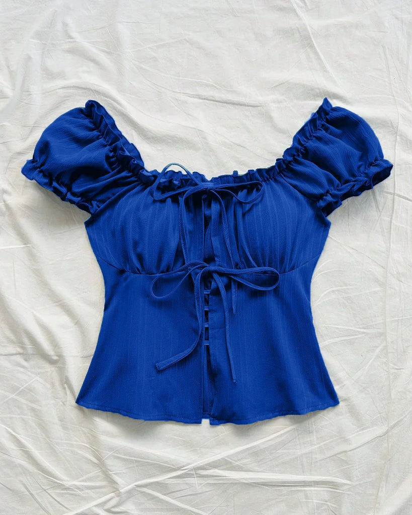 Royal blue blouse with ruffled puff sleeves and a tie front bow detail.