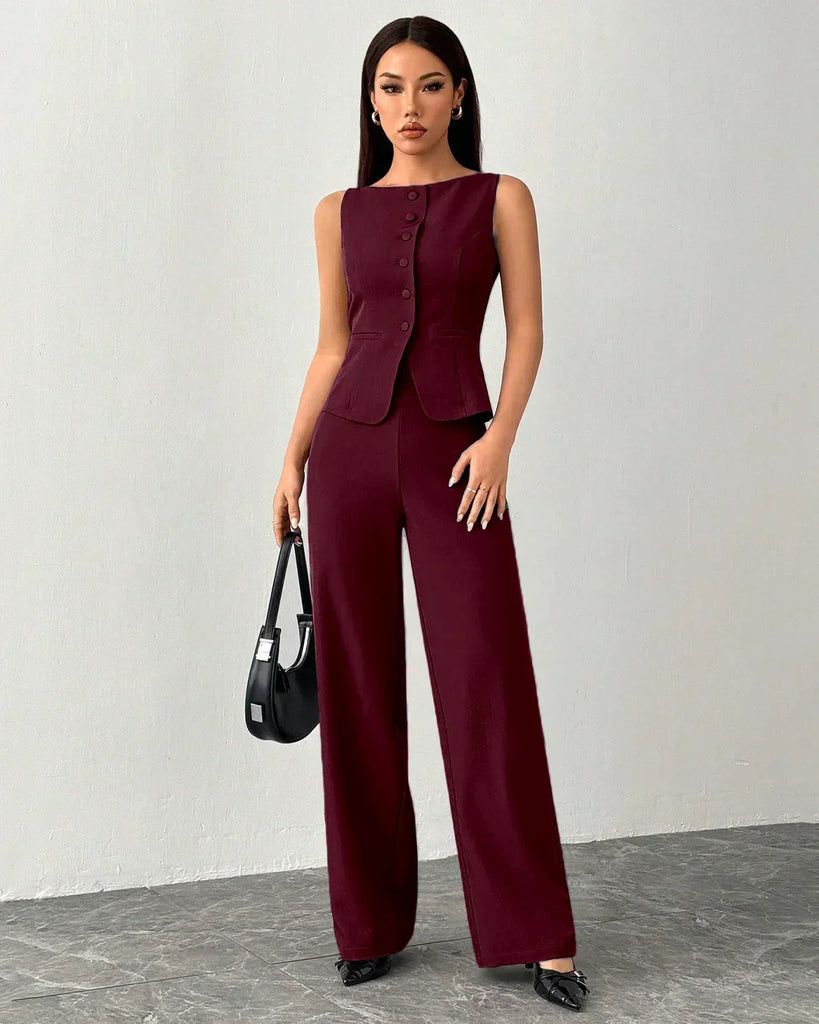 A woman models a sleeveless burgundy jumpsuit with a buttoned vest and wide-leg trousers.