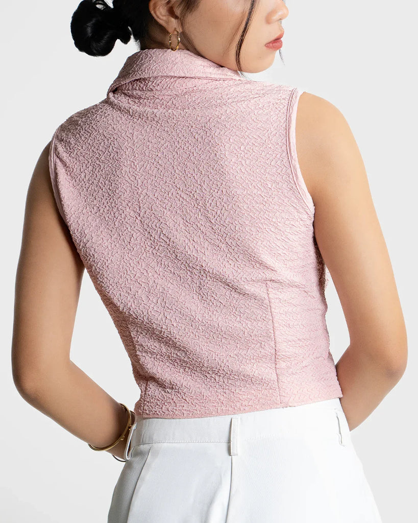 Person wearing Baby pink sleeveless collared crop shirt with front buttons, designed in a textured crinkle fabric for a stylish touch worn by a person