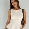 Front view of Sleeveless peplum top with fitted bodice and flared hem, designed to highlight the waist with a clean and stylish look