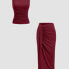 Two pieces of a maroon dress featuring a sleeveless ruched top and a matching midi skirt.