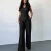 Model in a black sleeveless wrap top and wide-leg trouser matching set, showcasing a sleek and stylish look.