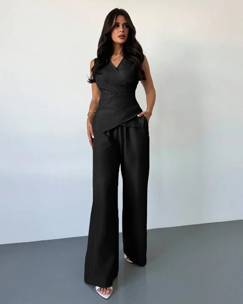 Model in a black sleeveless wrap top and wide-leg trouser matching set, showcasing a sleek and stylish look.