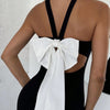 woman wearing a sexy, backless black dress featuring a prominent white bow tie detail