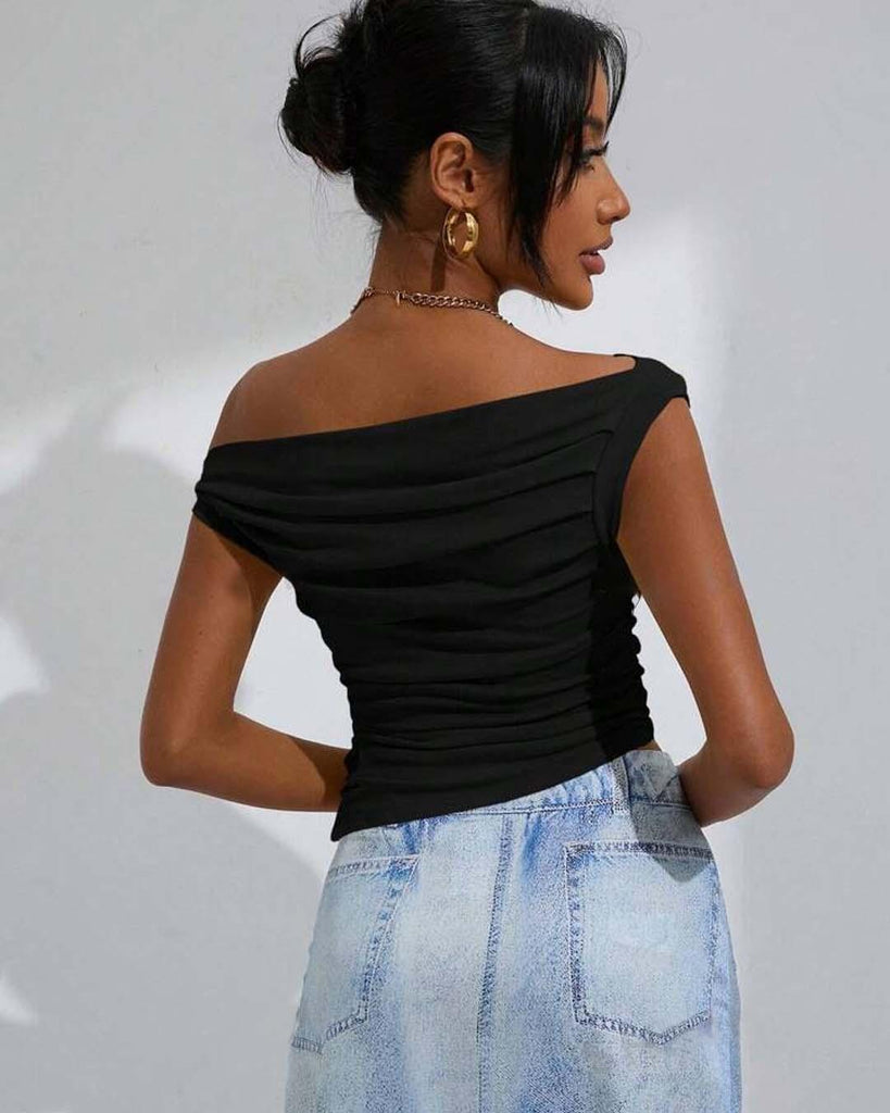 woman dressed in a black off-shoulder top paired with a denim skirt stands, highlighting her fashionable look back view