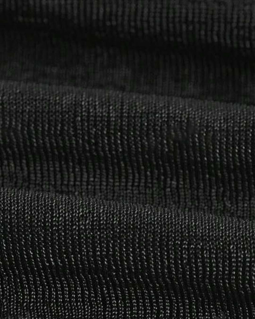 woman dressed in a black off-shoulder top paired with a denim skirt stands, highlighting her fashionable look close view