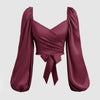 Burgundy top featuring a front bow, solid color lantern sleeves, and a braided tie back with pleats in cherry red.