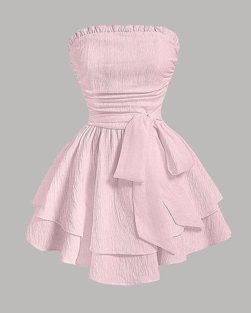 Front view of Baby pink strapless dress in a solid color with a fitted bodice, waist belt, and layered flared skirt for a party look.