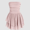 A powder pink tube dress featuring a ruched bust and ruffle detailing for a soft, sculpted silhouette.
