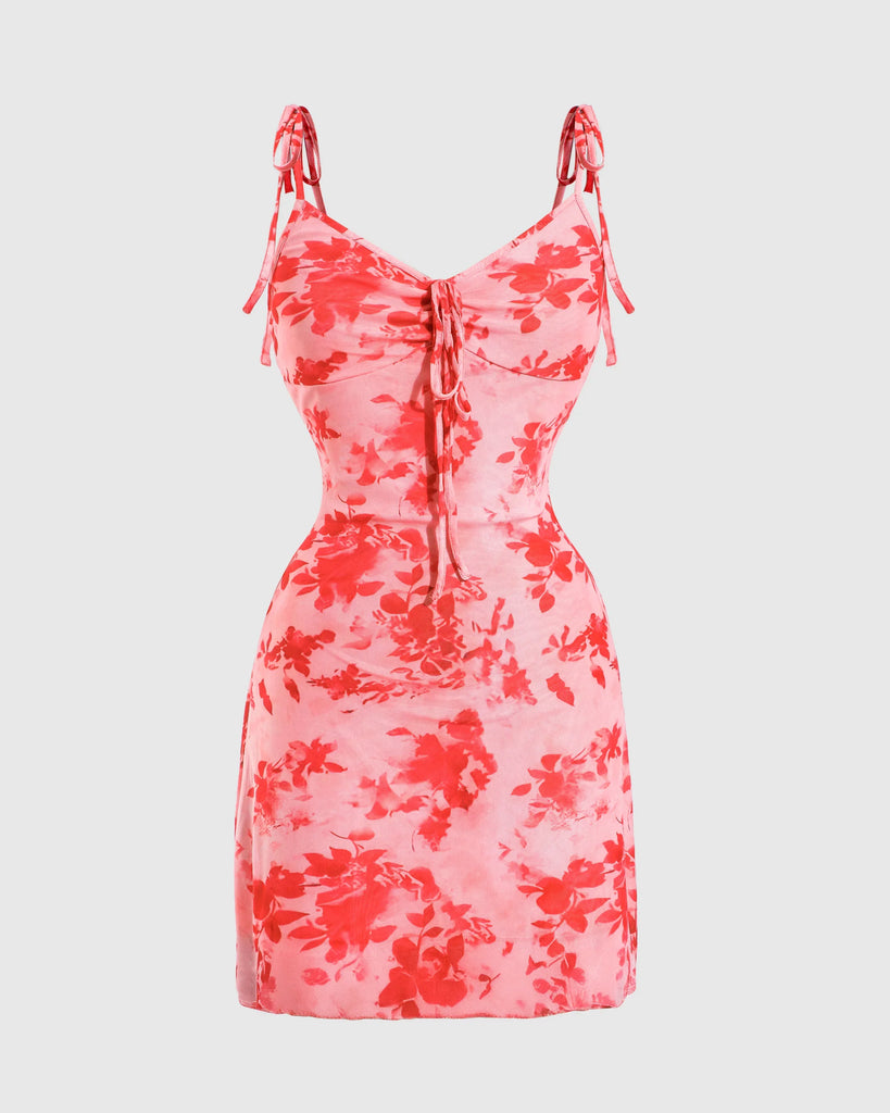 A baby pink spaghetti strap mini dress featuring red and white floral patterns on a mesh fabric.