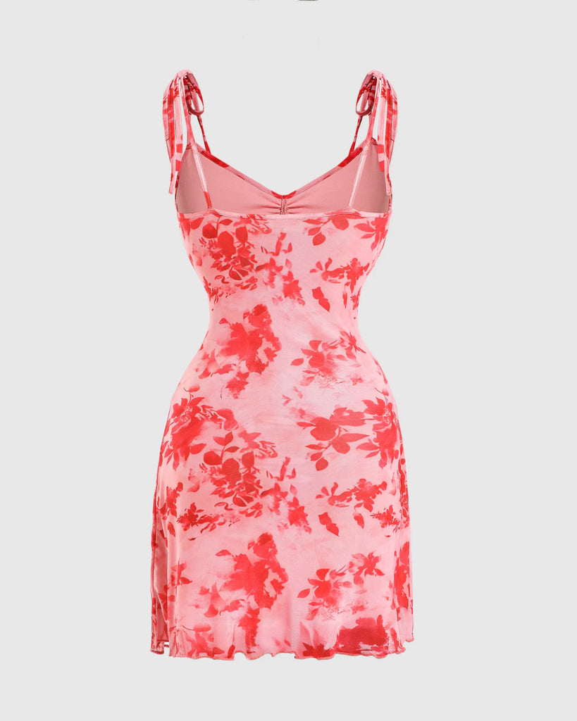 Back view of a  baby pink spaghetti strap mini dress featuring red and white floral patterns on a mesh fabric.