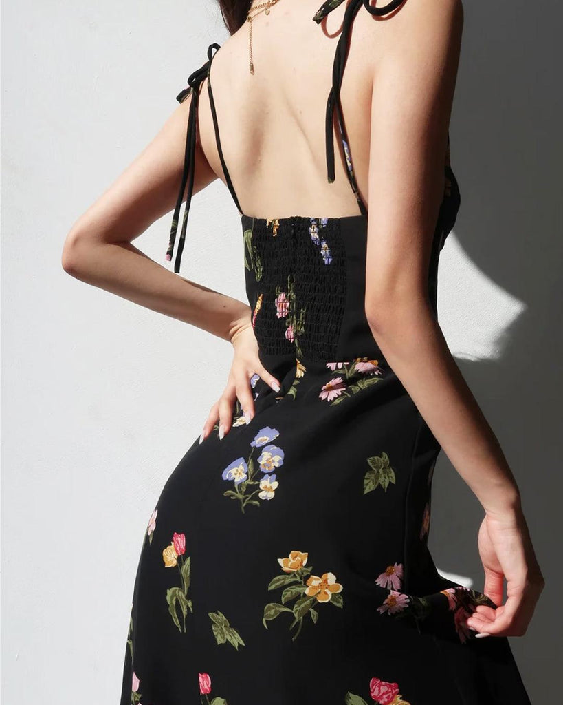 woman wearing black floral spaghetti strap dress with a side slit back view