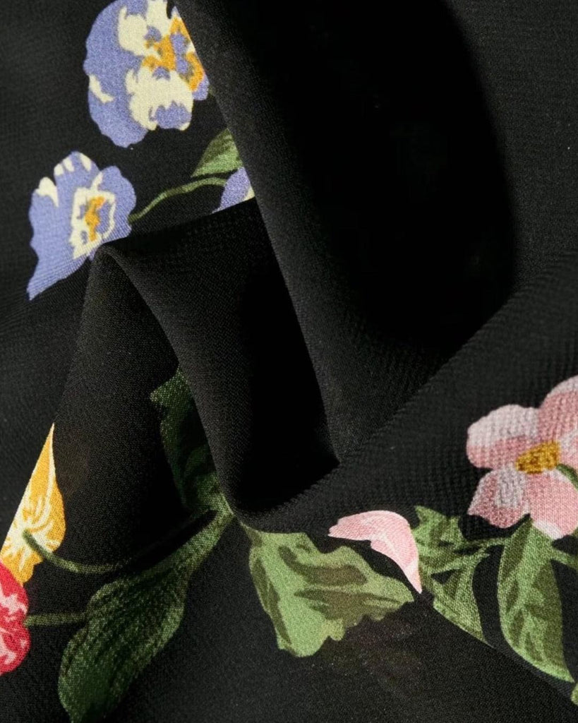 woman wearing black floral spaghetti strap dress with a side slit close up view