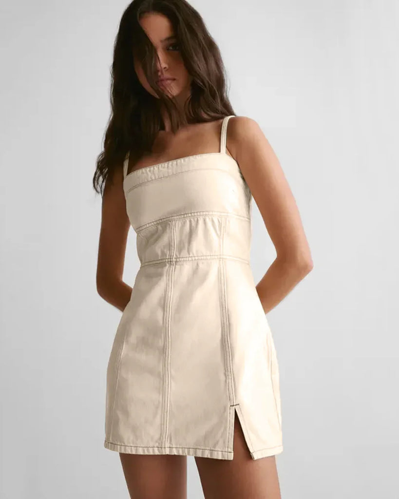Model in a white spaghetti strap mini dress with a square neck and side slit, showcasing a stylish and elegant look.