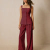 Model showcases a burgundy square neck sleeveless co-ord set with front buttons, paired with wide-legged pants.
