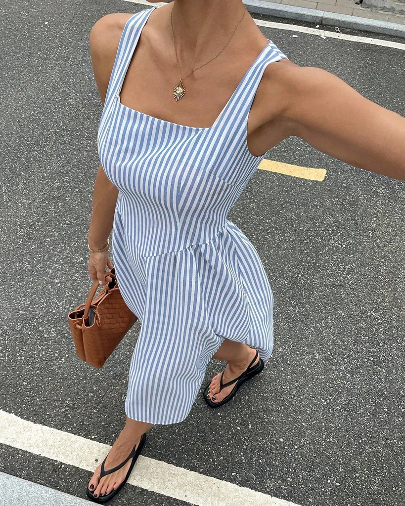 a blue and white striped midi dress with spaghetti straps and a square neckline.