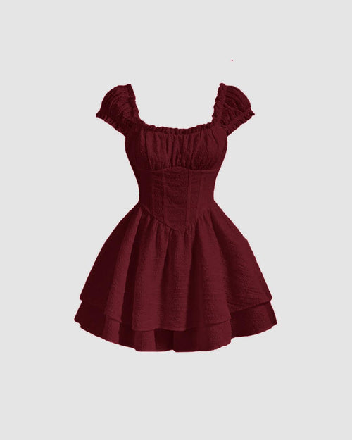 Front view of Maroon waist-cinching fit and flare dress with puff sleeves, corset-style bodice and layered ruffle mini skirt.
