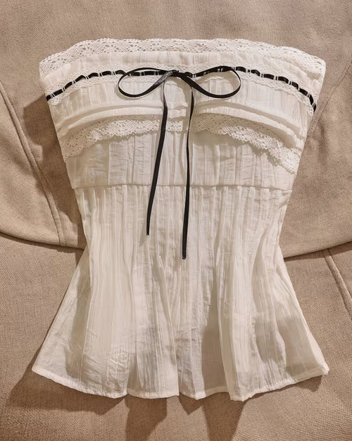 Front view of white colour top strapless lace ribbon bow design with pleated fabric and fitted silhouette.