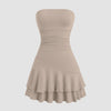 A beige strapless mini dress featuring ruched detailing and layered fabric for a soft, sculpted silhouette.