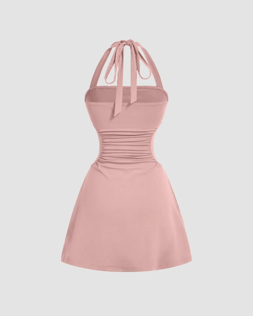 Back view of a Pink halter mini dress with a tie around the neck, featuring a fit and flare design and strappy back.