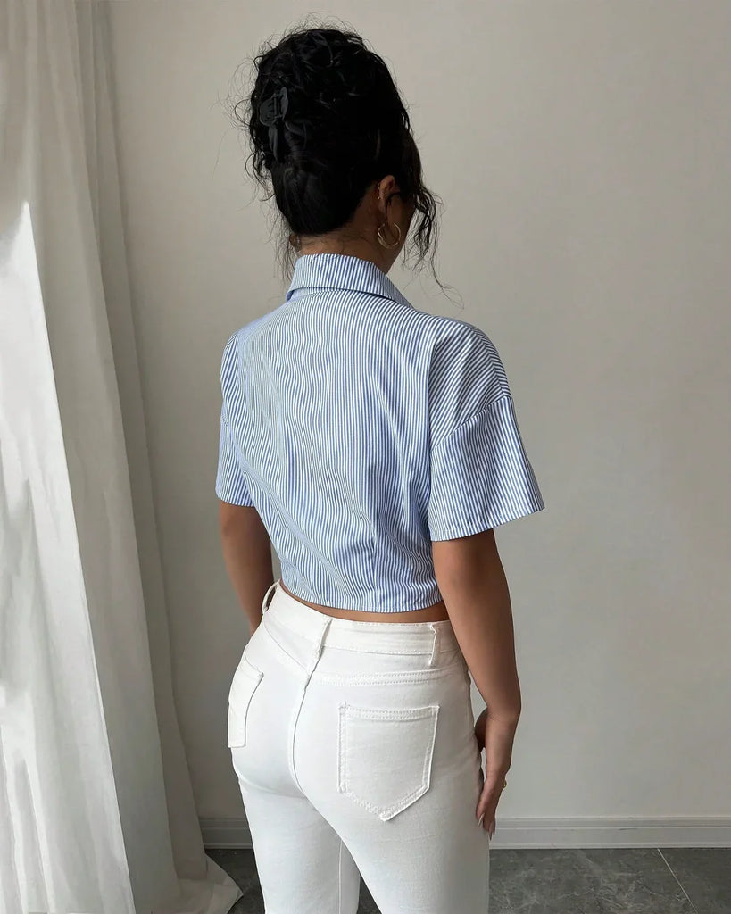 Women showing the back of A ruched crop striped collar shirt in blue, paired with white jeans, showcasing a stylish and casual look