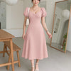 Front view of a woman in Powder pink cotton dress with puff sleeves and cinched waist, perfect for summer elegance.