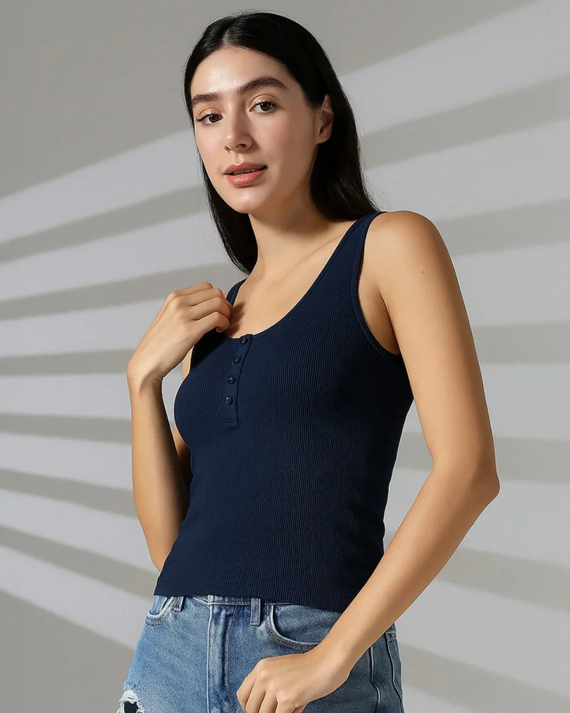 Model wearing a navy blue ribbed tank top with a scoop neckline and button-down front. Sleeveless and slim-fitting, made from breathable fabric for a comfortable yet structured look.