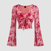 Front view of Floral print pink crop top with long bell sleeves and a stylish tie detail at the waist.