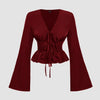 Front view of a red long sleeve top with a deep V-neck, tie-front ruching, and flared sleeves on a plain background.