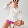 Women wearing white pleated shirt with long sleeves, structured fit and button front design