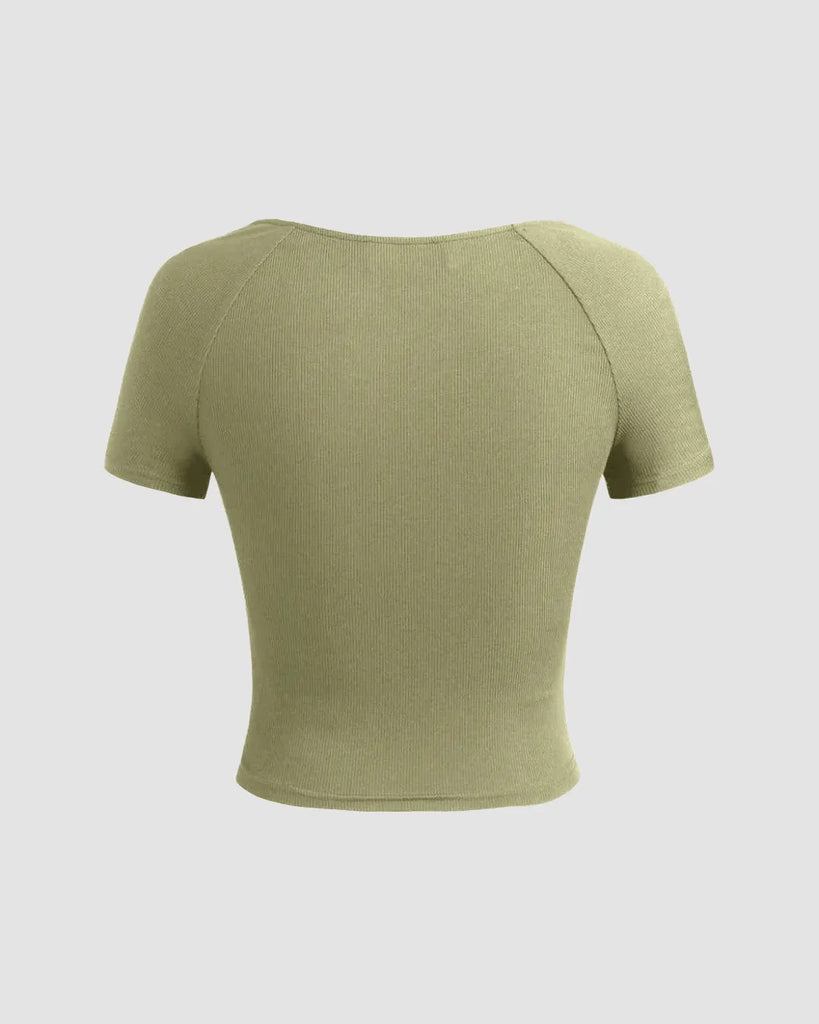 Sage green ribbed V-neck wrap top with short sleeves and a cinched waist, offering a flattering fit and soft structure on a light grey background