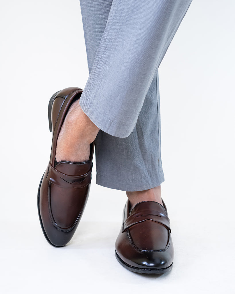 A model crossing legs wearing Synthetic Leather loafers
