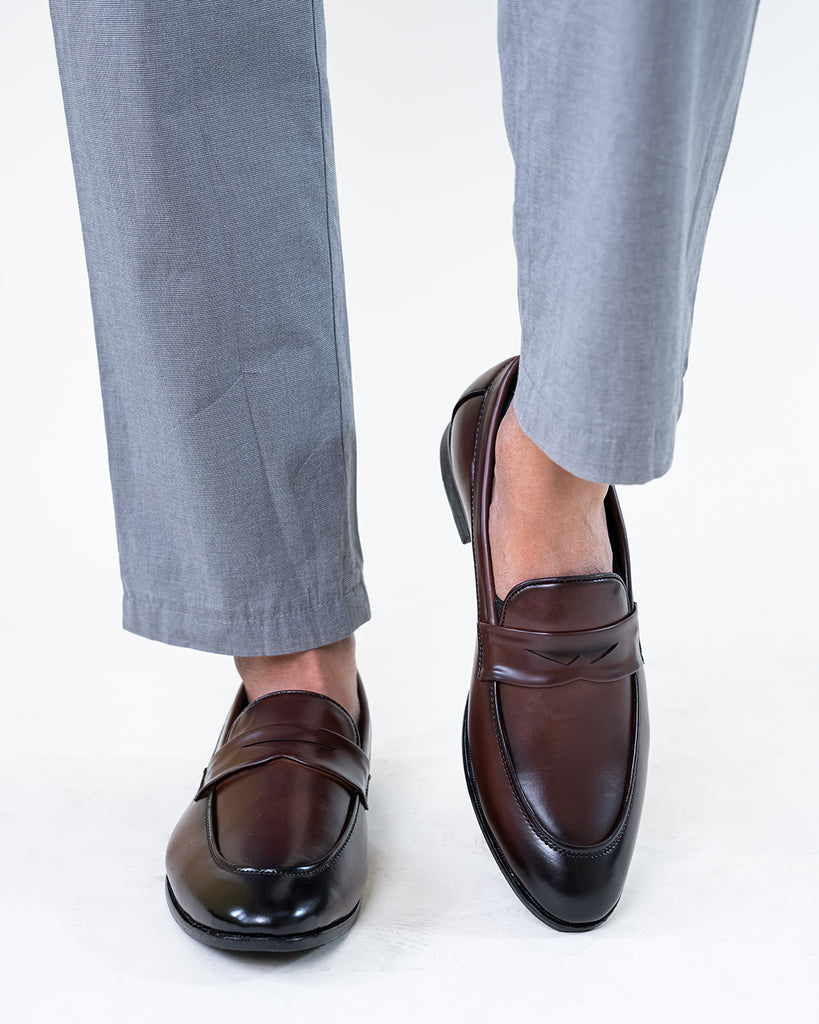 A model walking wearing a brown Synthetic Leather loafers.