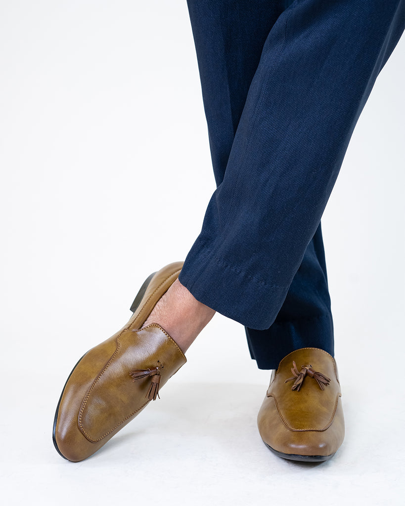 A model crossing his leg wearing a pair of loafers